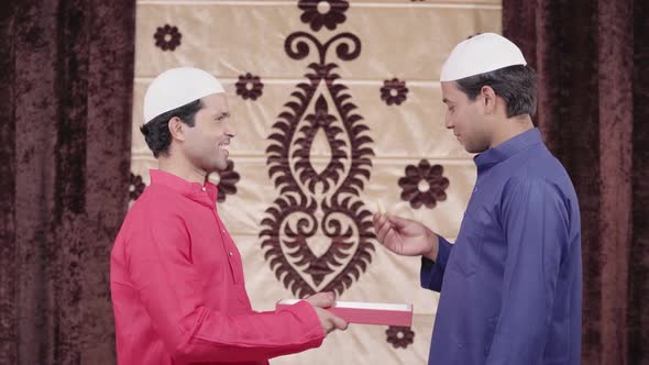 Man giving sweets to his friend on Eid