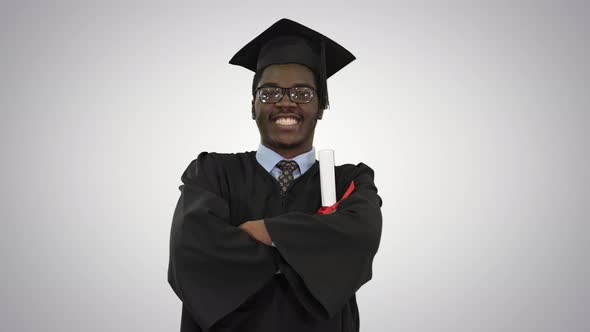 African American Male Student in Graduation Robe Folding Arms with Diploma Looking with a Big Smile