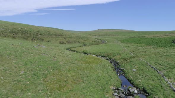 Wide aerial tracking forward along a river and stone wall beside the famous wistmans wood in the hea