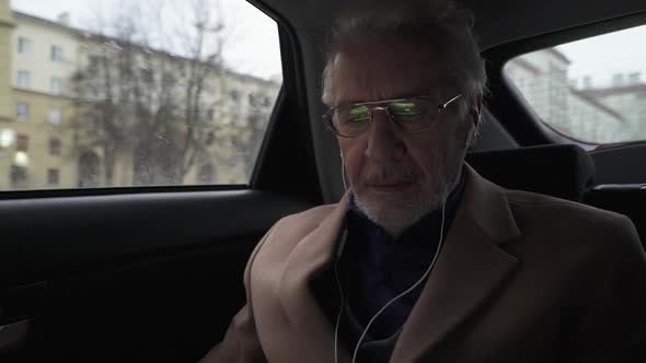 Portrait of an Gray Haired Man with Glasses Looking at a Laptop Screen a Focused Architect Works on