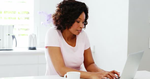 Woman using laptop in kitchen 4k