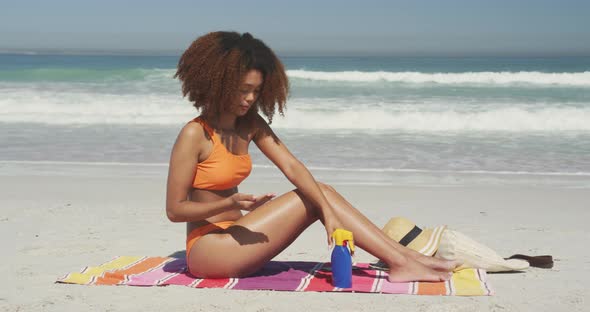 African American woman applying sunscreen at beach