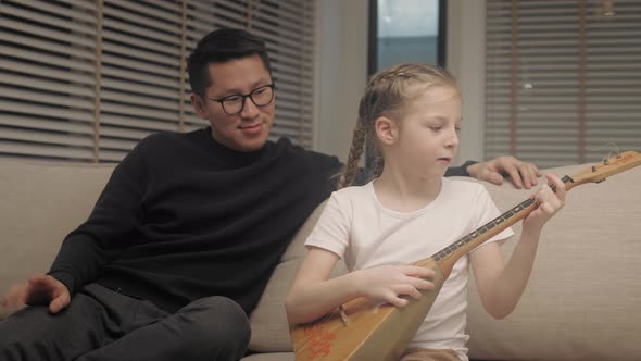 Girl playing the guitar on the couch at living room