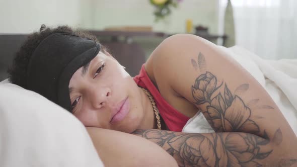 Close-up View of Pretty African American Woman Lying Under White Blanket with Black Sleeping Mask