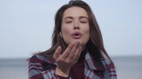 Charming Brunette Woman Sending Air Kiss at Camera and Smiling. Close-up Portrait of Brunette