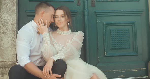 Romantic wedding couple sitting against green door in old town in Montenegro.