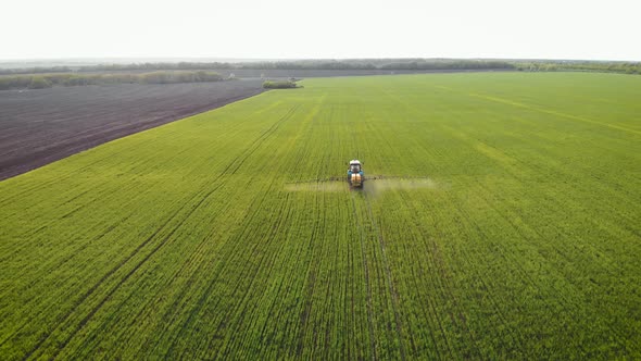 Aerial View of Farming Tractor Spraying on Field with Sprayer, Herbicides and Pesticides at Sunset