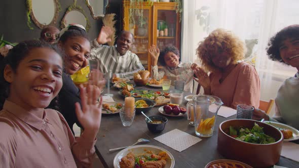 Joyous Family Smiling and Waving on Camera at Home Dinner