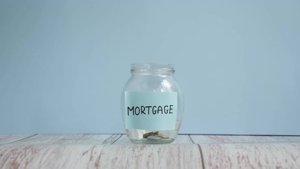 Saving money concept. Save money to buy new house. Glass jar with inscription mortgage