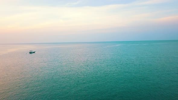 drone shot over the ocean crossing a fisherboat during golden hour in Langkawi Malaysia