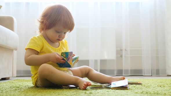 Curious Cute Preschool Redhead Girl Sitting on Carpet Floor Alone and Reading Book