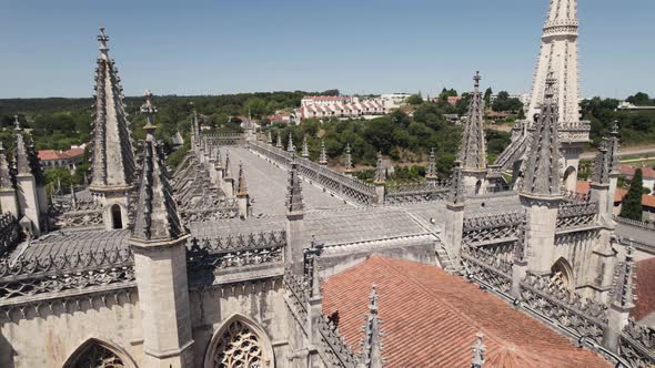 Drone flying over rooftop with gothic spires of Batalha monastery. Aerial orbit