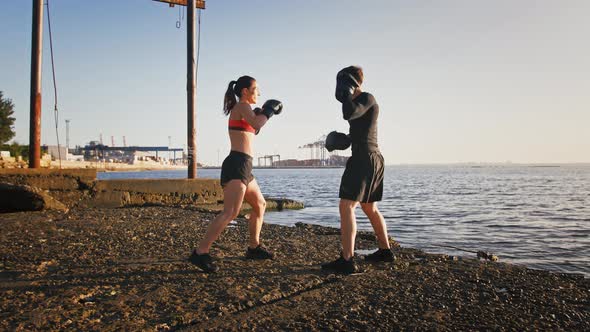 Young Athletic Lady in Boxing Gloves and Sportswear is Boxing a Paw of Her Experienced Trainer