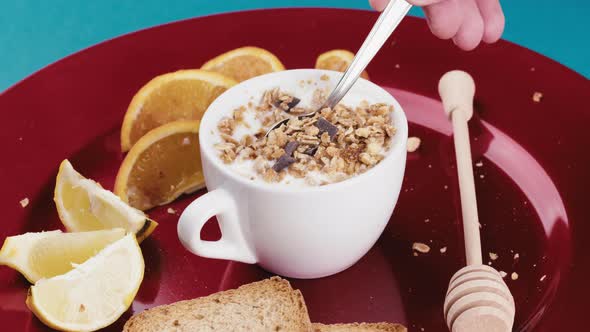 Red Plate with Spoon That Mixes Plain Yogurt and Granola in a Cup