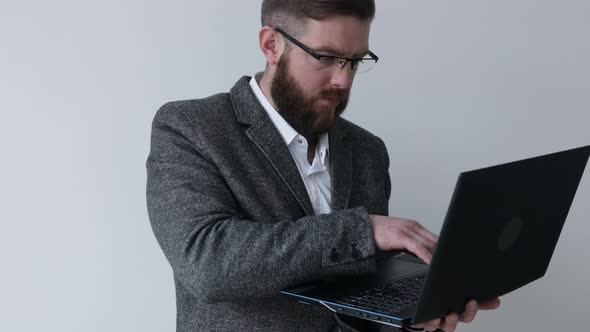 Close up view of bearded middle aged man in glasses using laptop computer