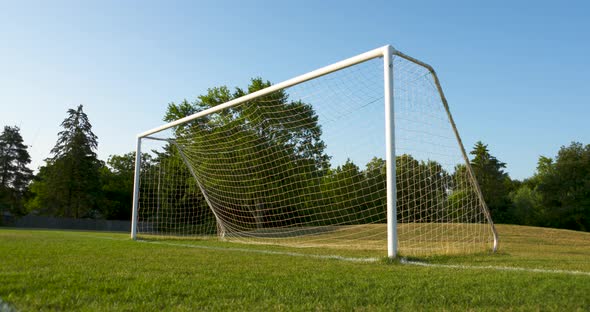 Low angle shot of a soccer net and field on a sunny, summer morning