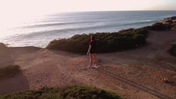 Sportswoman admiring seashore at sunset