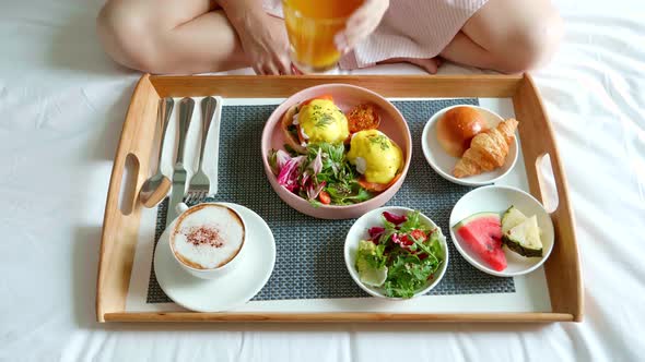 Woman Eating Breakfast in Bed in Cozy Hotel Room