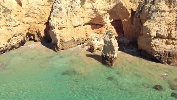 Cliffs and caves of pristine Atlantic Ocean coast,  Lagos, Algarve, Portugal. Aerial pullback