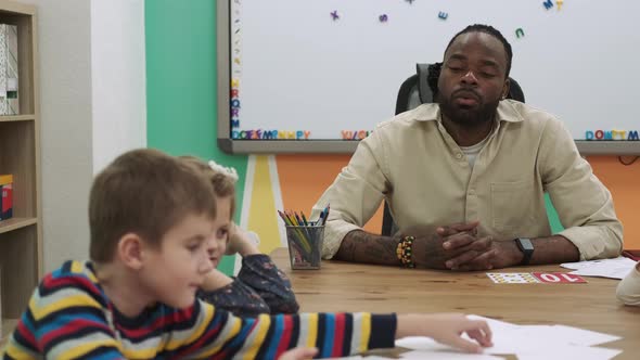 An African American Teacher Teaches a Group of Children Numbers Using Flashcards