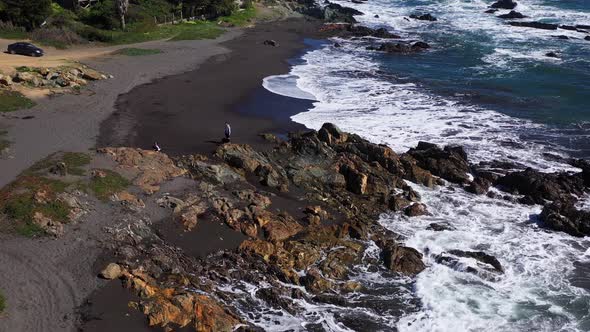 aerial view of a father playing with his children and family on the infiernillo beach with black san