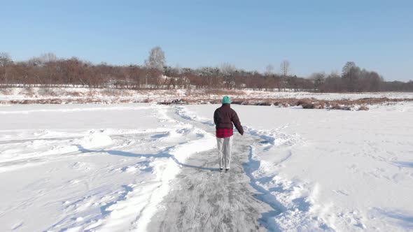 Woman is skating on frozen pond or river
