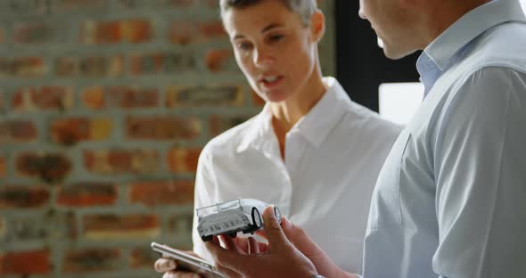 Car designers discussing over model car and digital tablet