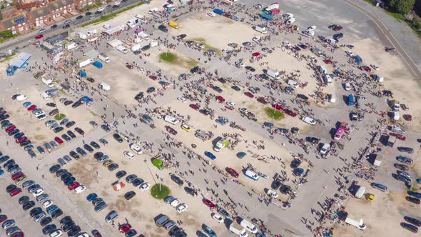 Aerial clockwise hyper-lapse rotation around a busy market in Hull and car boot sale showing people