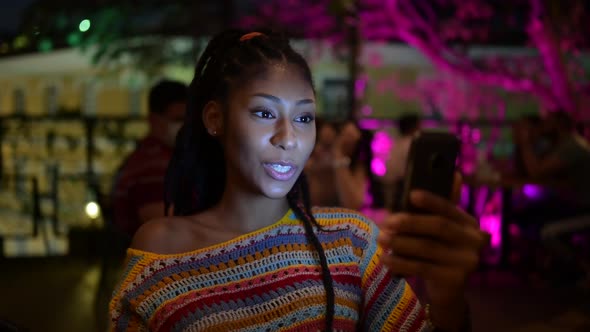 Black woman talking on video call on smartphone in evening city