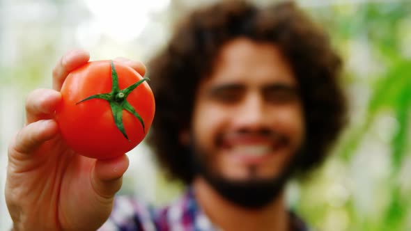 Happy man showing fresh tomato