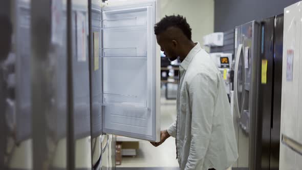 A Man Inspect the Design and Quality of Fridge Before Buying in a Consumer Electronics Store
