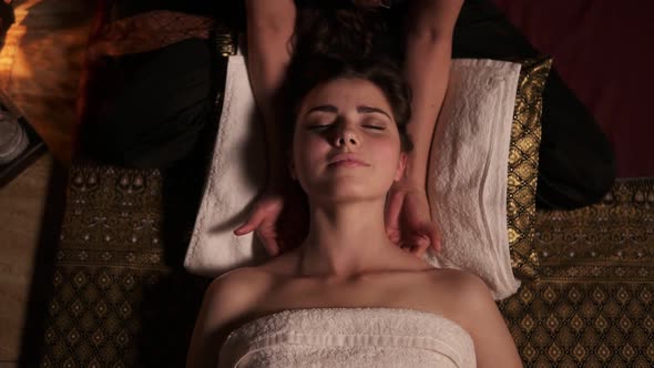 Young Woman with Her Eyes Closed Having Thai Massage of Her Neck and Shoulders in Spa By