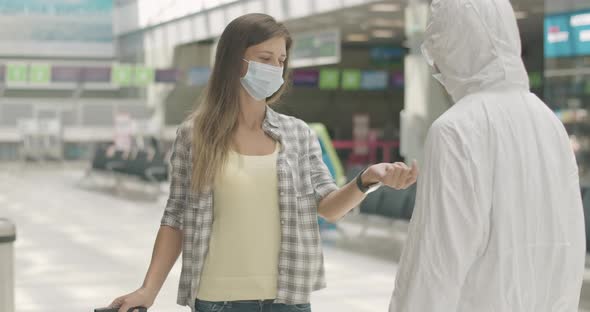 Airport Employee Measuring Temperature on Hand of Brunette Caucasian Woman in Face Mask. Tourist