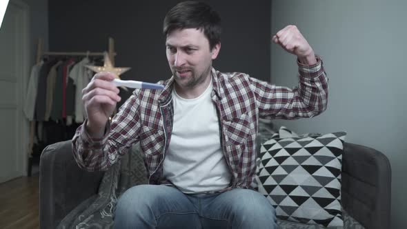 One Happy and Joyful Caucasian Man Holding Pregnancy Test at Home