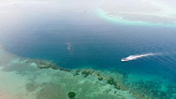 A dive boating through pristine ocean water and coral reefs leaving wake in its trail at stunning re