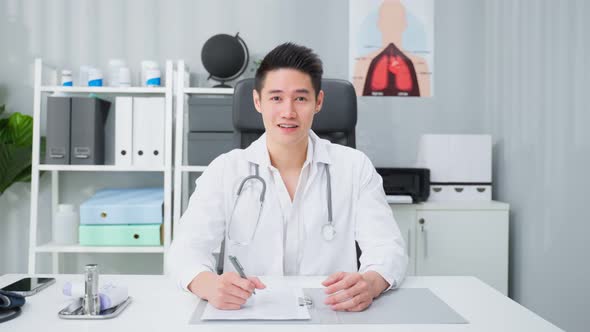 Portrait of handsome physician doctor sit on table in office hospital.