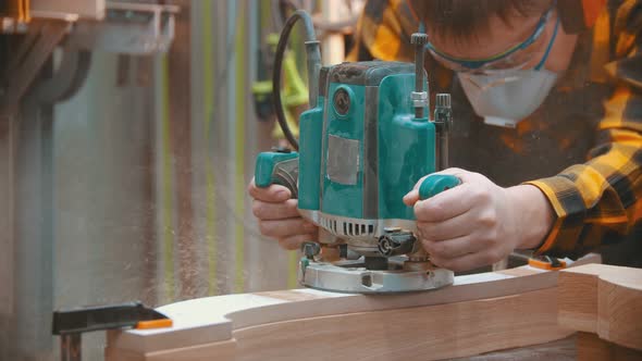 Man Woodworker Polishes a Wooden Plank with a Special Equipment