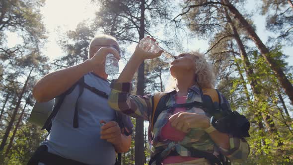 Senior Couple Having Drink From Bottle On Walk in Woods