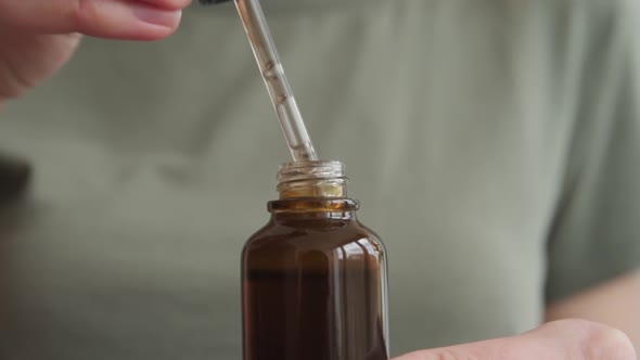 Woman Holds Bottle with Cosmetic Serum and Essential Oil