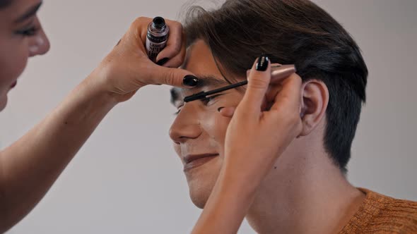 Make Up Artist Doing a Brown Bold Lips Look on Her Male Model - Applying Mascara on His Eyelashes