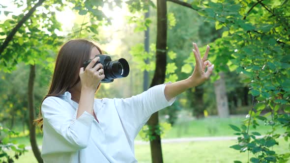 Pretty Girl Photographer in White Shirt Is Making Photos and Before Taking a Picture She Shows on