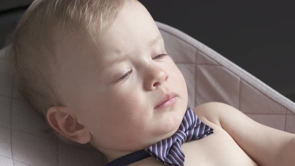 Cute Small Child Face Closeup One Year Old Baby Boy Wearing a Bow Tie Lying in Rocking Chair for