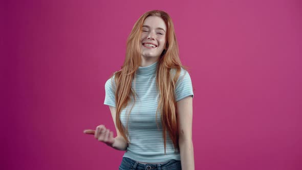 The Young Redhead Demonstrates Her Good Mood By Displaying a Wide Smile and the Like Sign in a Blue