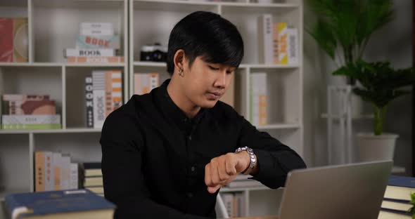 Asian businessman checking time while sitting at workplace desk