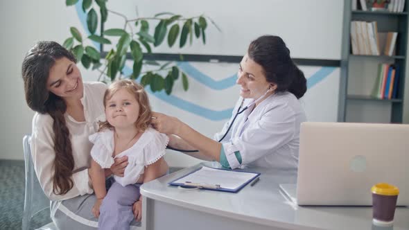 Friendly Doctor Pediatrician Using Stethoscope Listen To the Heart of Happy Healthy Cute Kid Girl