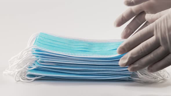 Nurses' Hands Remove a Stack of Medical Masks From a White Sterile Surface. Medical Mask Closeup on