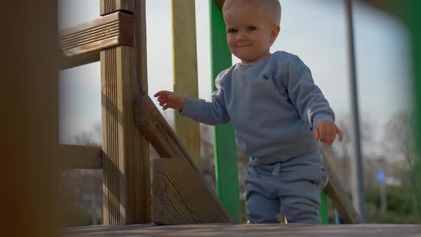 Cute Toddler Climbs Out on Wooden Construction at Playground