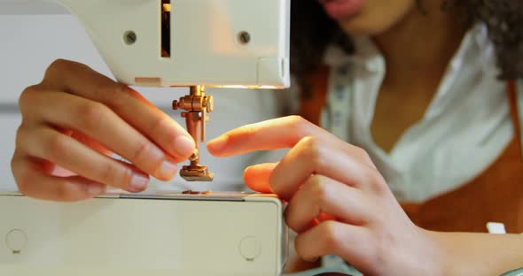 Front view of African American female fashion designer working with sewing machine in workshop 4k