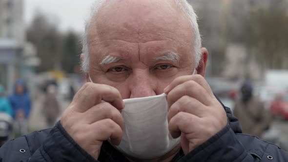 Portrait Elderly Man Puts Protective Medical Mask On His Face From Coronavirus