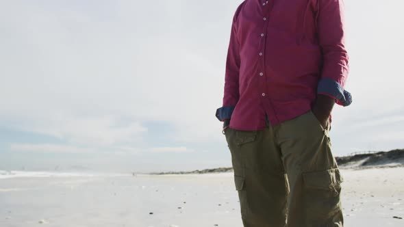 African american man walking on a beach in thought looking at the sea